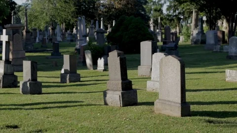 Walking through grave yard at sunset. Head stones and marble monuments of the de Stock Footage 111399648