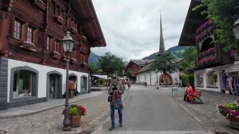 Walking Through Gstaad Street with Chalets and Church Spire Stock Footage 340369790