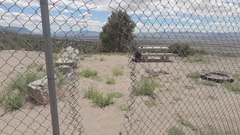 Walking Through Hole In Chain Link Fence: Picnic Table, Fire Pit, Nevada Desert Stock Footage 148117126