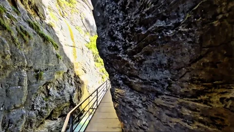Walking Through Narrow Rocky Gorge on Cliffside Walkway Stock Footage 344878274
