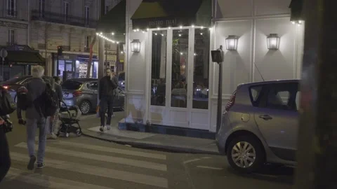 Walking through Paris at night, busy street near a bistro with pedestrians and Stock Footage 306681289