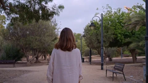 Walking through a park with trees and benches during the day near a city Stock Footage 342786583
