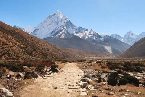 Walking through Pheriche valley, Pheriche village in the distance in front .. Foto stock