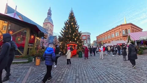 Walking through Riga Old Town Christmas market with a towering decorated tree Stock Footage 327424432