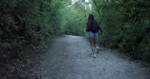 Walking through a serene forest path during twilight, a girl enjoys nature and Stock Footage 346664399