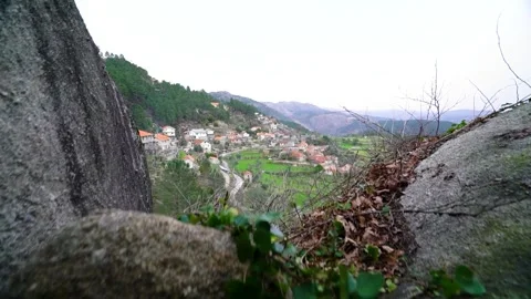 Walking through a small natural stone tunnel to see a mountain village Stock Footage 264090229