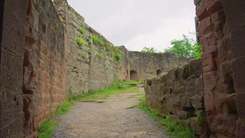 Walking through a stone arch into an old, plant-covered castle courtyard. Stock Footage 309357702