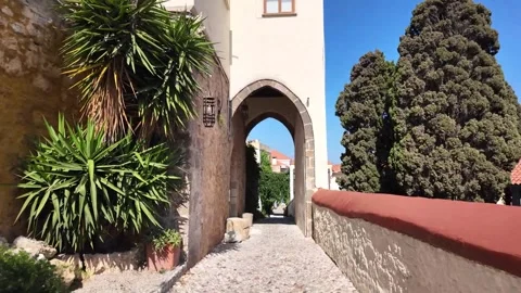 Walking towards stone archway on cobblestone path in Rhodes, Greece Stock Footage 340575832