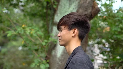 Walking Tracking Shot - Happy Young Asian Man Walking in Park Stock Footage 104996996