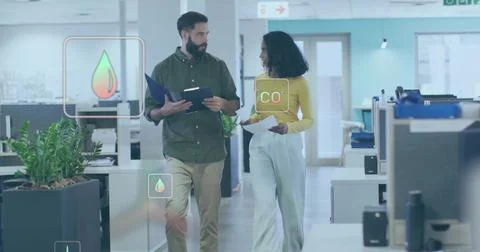 Walking two colleagues in open-plan corridor, holding blue folder and papers, Stockfoto's