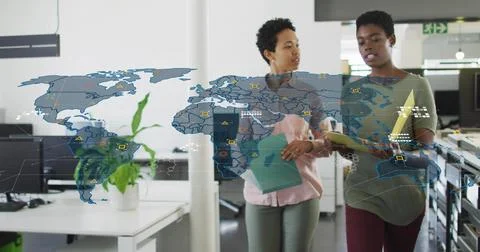 Walking two professionals reviewing document folders in open-plan office, with 스톡 사진