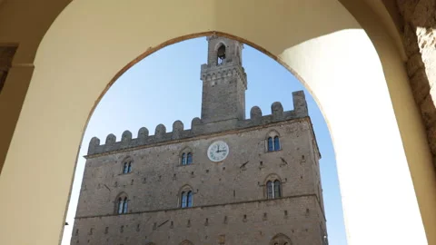 Walking under an arcade in the old town with the Palazzo Dei Priori in Volterra. Stock Footage 169604855