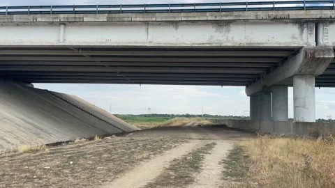 Walking under the highway bridge on a field road Stock Footage 203772024