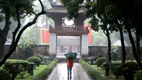 Walking into a Vietnamese buddhist temple while raining, with an umbrella Stock Footage 100318085