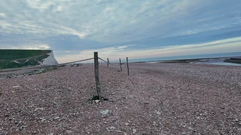 Walking View Along Pebble Beach with Wooden Groynes and Distant White Cliffs Stock Footage 309767231