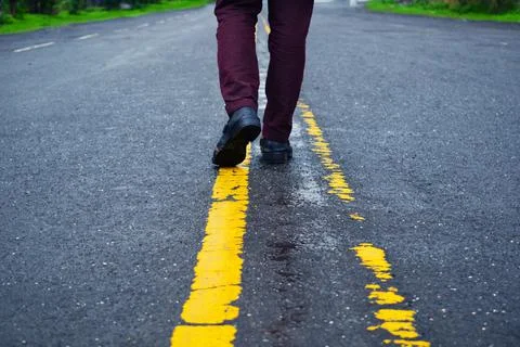 Walking way, Close up view on man's legs in jeans and black leather shoes. Stock Photos