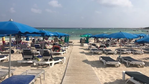 Walking on Wooden Path at the Beach with Blue Sunbeds and Umbrellas Stock Footage 101248479