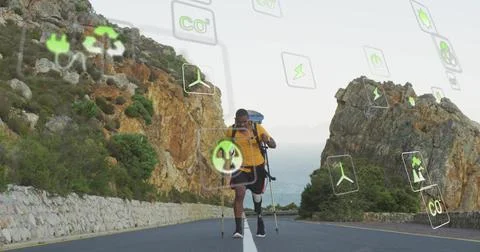 Walking yellow shirt using poles carrying pack on coastal road with prosthetic Stock Photos