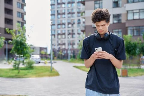 Walking young guy using smartphone, modern city street background Stock Photos