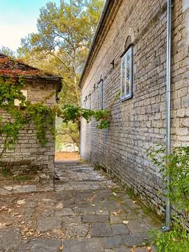 Walkway between two stone homes leading to a leaf covered road in Greece Stock Photos