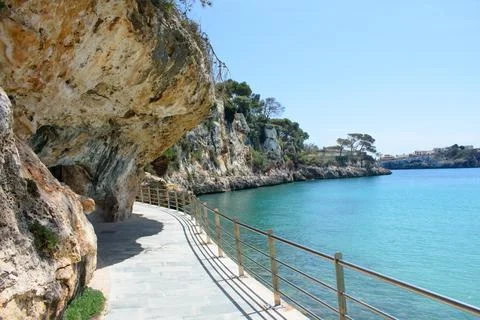 Walkway with railing next to coastal cliffs in Porto Cristo Stock Photos