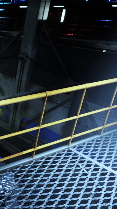Walkway view inside a factory with yellow railing and metal grates at night Stock Footage 337901497
