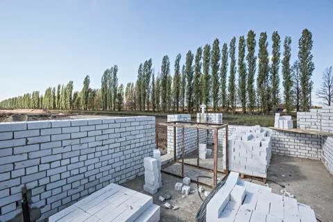 Wall and bricks at construction site with diminishing trees in the background Stock Photos