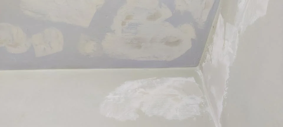Wall and ceiling corner with putty patches and off white base color Stock Photos