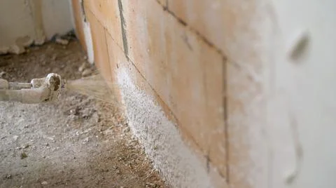 A wall being covered in a layer of plaster. LD Plaster being sprayed onto an  Stock Photos