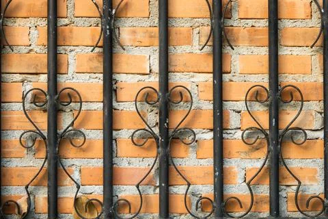A wall with a black iron gate with a pattern of swirls Stock Photos