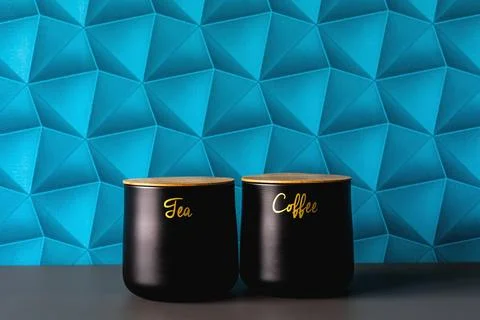 A wall with blue patterned wallpaper. Black containers for storing sugar, t.. Stock Photos
