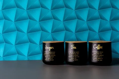 A wall with blue patterned wallpaper. Black containers for storing sugar, t.. Stock Photos