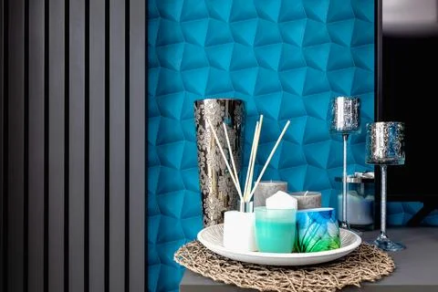 A wall with blue patterned wallpaper. Decorations on a grey table. Scented .. Stock Photos