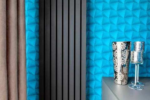 A wall with blue patterned wallpaper. A modern gray radiator. Decorations m.. Stock Photos