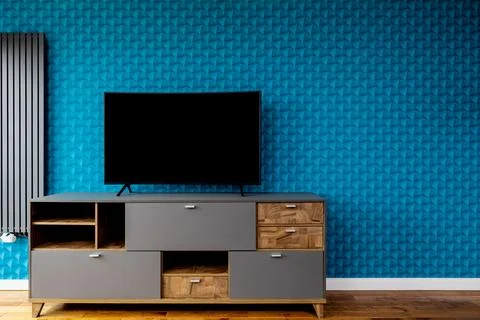 A wall with blue patterned wallpaper. A modern gray radiator. A dresser wit.. Stock Photos