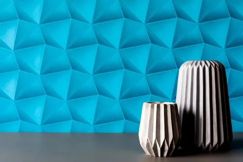 A wall with blue patterned wallpaper. Stone candle holders in gray color. R.. Stock Photos