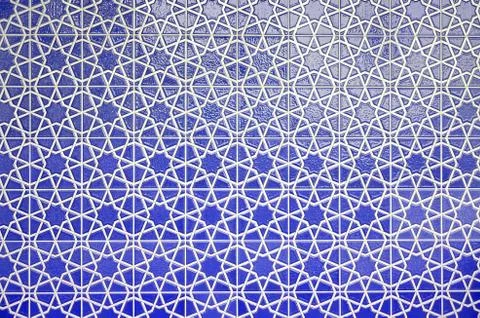 Wall of blue tiles with white pattern, drawing of white intersecting lines Stock Photos
