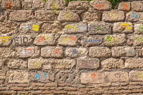 Wall of bricks with colored inscriptions and hearts Stock Photos
