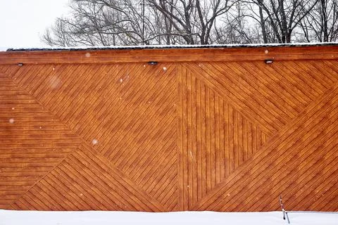 The wall of a building with a pattern of boards during a snowfall. winter lan Foto stock