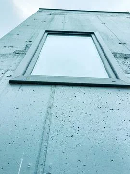 A wall of a building shows a window positioned high. The view is directed upw Stock Photos