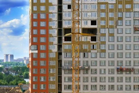 Wall of a building under construction with workers in construction cradles Foto stock