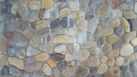 Wall built of rounded colored stones. stone wall texture &amp; pattern Stock Photos