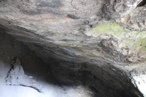 Wall of a cave in the nature with a stone in front Stock Photos