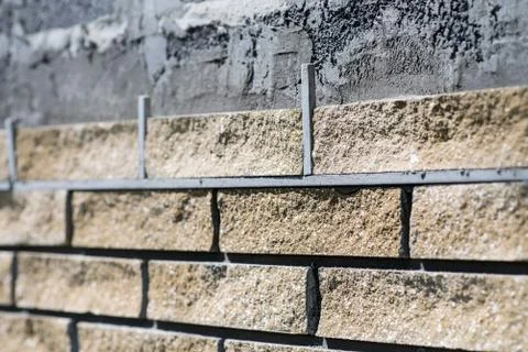 Wall cladding, angle view, process close up. Decorative bricks with rocky relief Fotos Stock