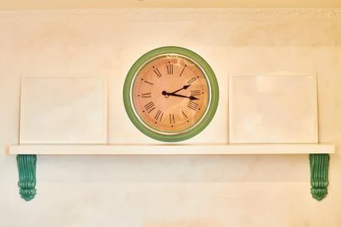 Wall clock on beige background. Shelf with frames from patterns and copy spac Foto stock