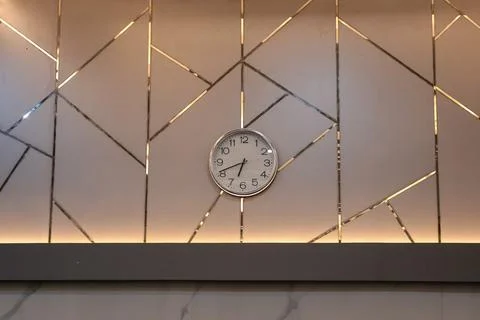 Wall Clock Displaying Time on Decorative Geometric Wall with Natural Light .. Foto stock