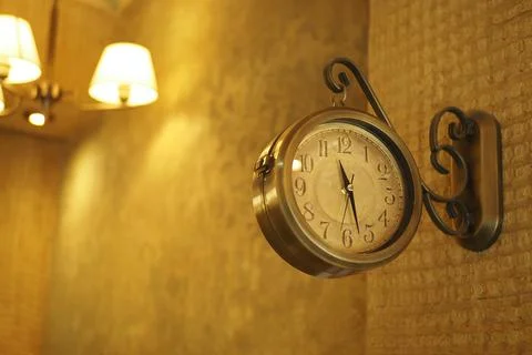 Wall clock hanging in a cozy cafe setting in the evening Photos