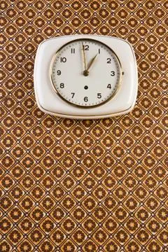 A wall clock hanging on patterned wallpaper Foto stock
