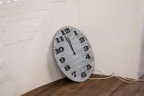 Wall Clock Leaning Against a Rustic White Brick Wall Stock Photos