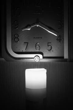 Wall clock lit by a candle Stock Photos
